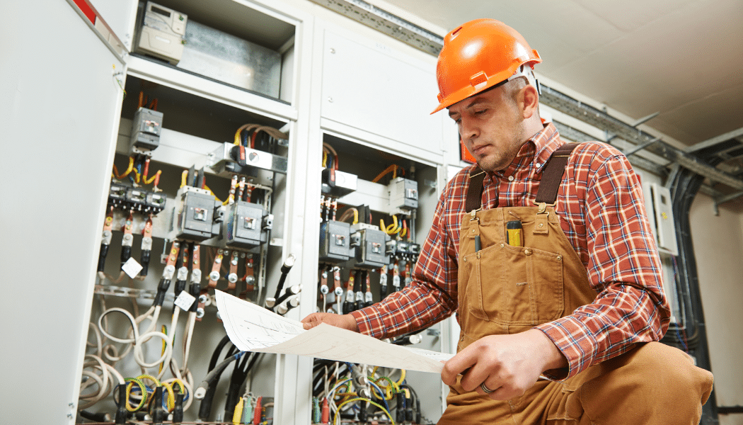 électricien devant un tableau électrique qui regarde un plan