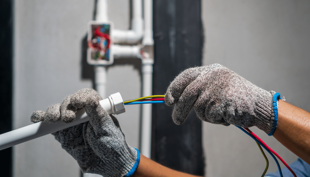 électricien qui rentre des câbles électriques dans un tuyau