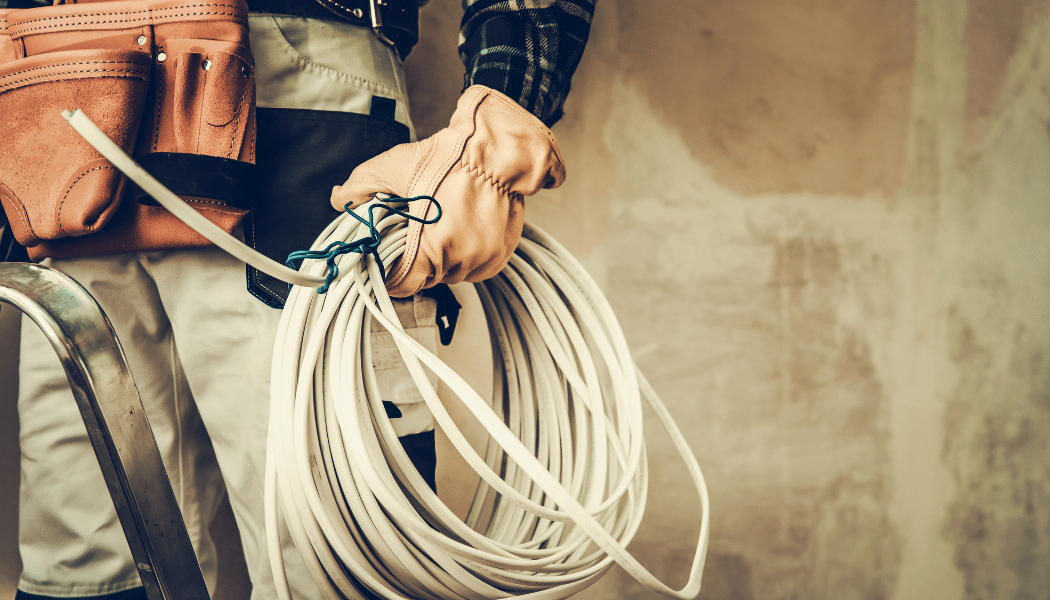 électricien qui tient un long cable entre les mains