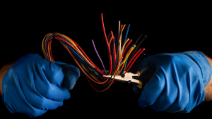 électricien qui tient dans ses mains une pince et des câbles